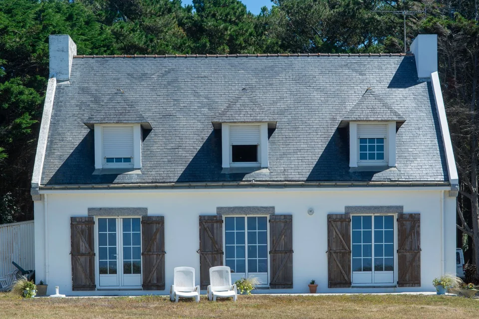 Maison blanche au toit d'ardoise, lucarnes et volets en bois